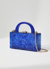Blue textured handbag with a chain detail on a light gray background