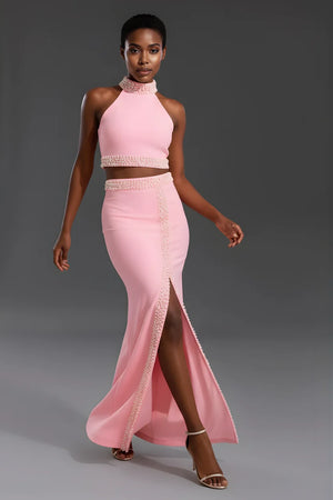 Model wearing a pink two-piece outfit with a high slit on a gray background