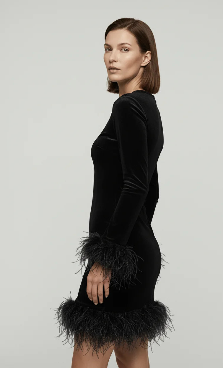 Woman wearing a black dress with feathered cuffs on a plain background