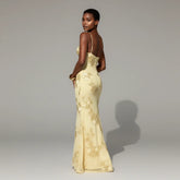 Woman wearing a yellow lace evening gown against a gray background