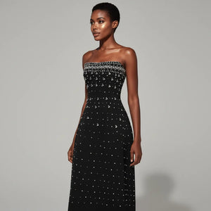 Black strapless dress with white embellishments on a gray background