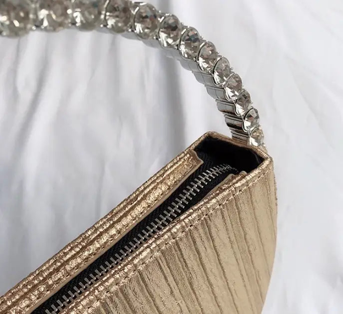 Gold clutch with crystal handle on a white background