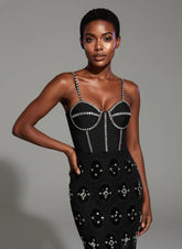 Woman wearing a black dress with silver embellishments against a gray background