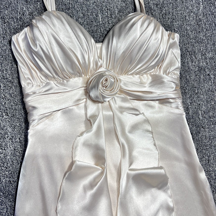 White satin dress with a floral bow on a gray surface