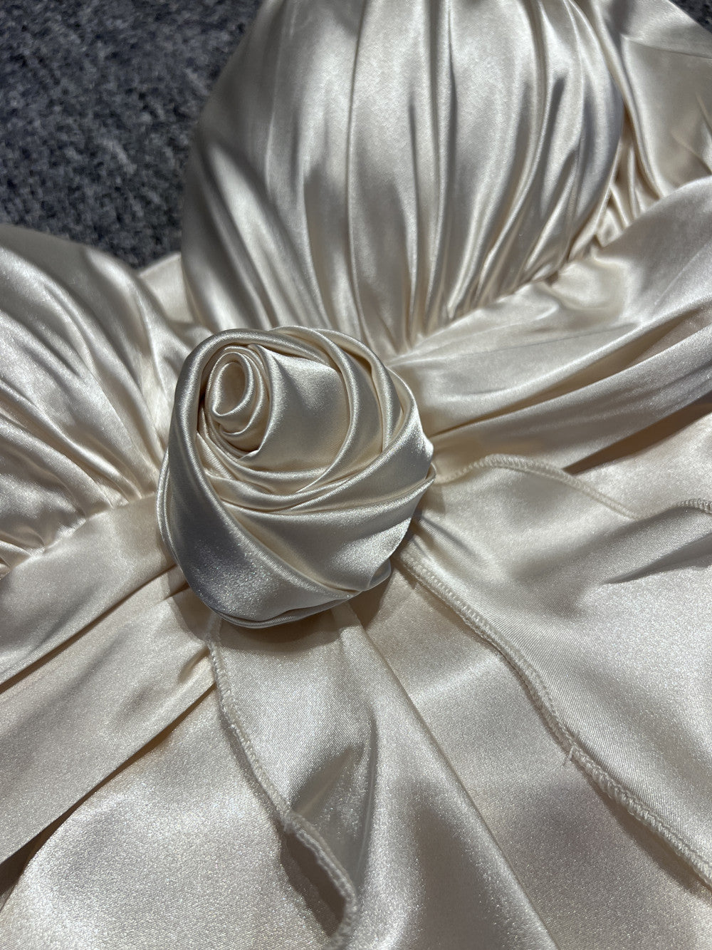 Close-up of a white satin fabric with a rose detail on a textured surface.