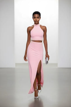 Model wearing a pink high-neck crop top and skirt with a slit on a white background