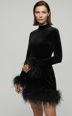 Woman wearing a black velvet dress with feather details on a gray background