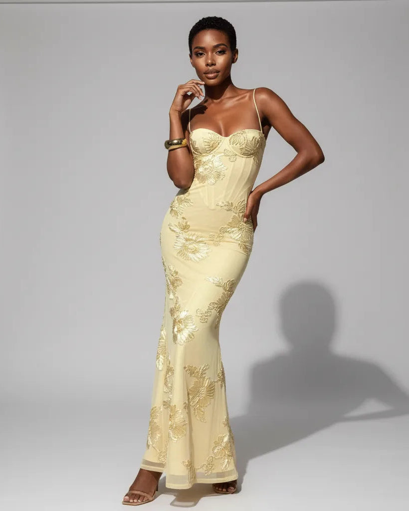 Woman wearing a light yellow lace evening gown against a gray background