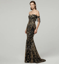 Woman wearing a black and gold evening gown with fringe details on a gray background