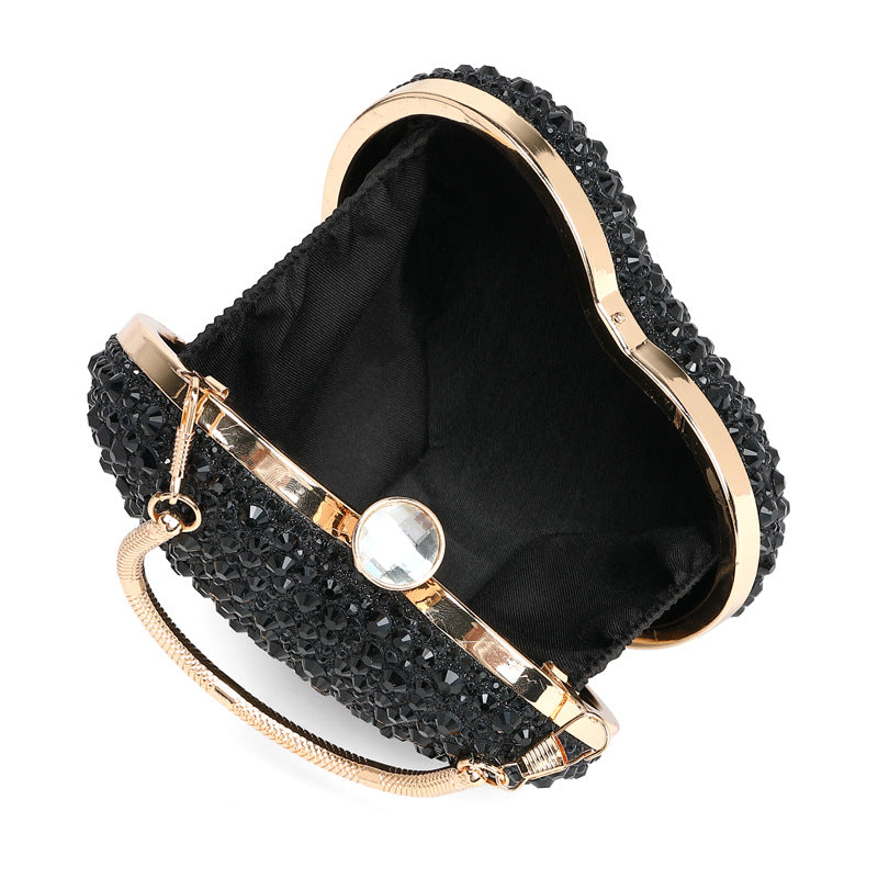 Black handbag with gold accents and a pearl-like clasp on a white background