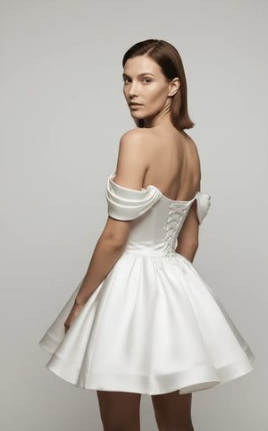 Woman wearing a white off-shoulder dress against a gray background