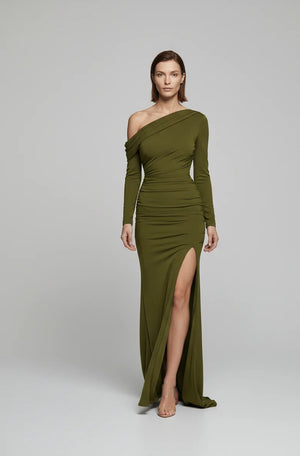 Woman wearing a green one-shoulder dress with a slit on a white background