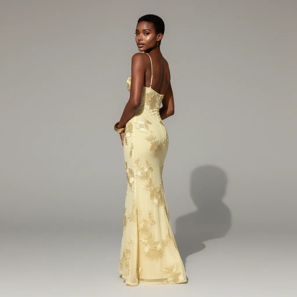 Woman wearing a yellow lace evening gown against a gray background