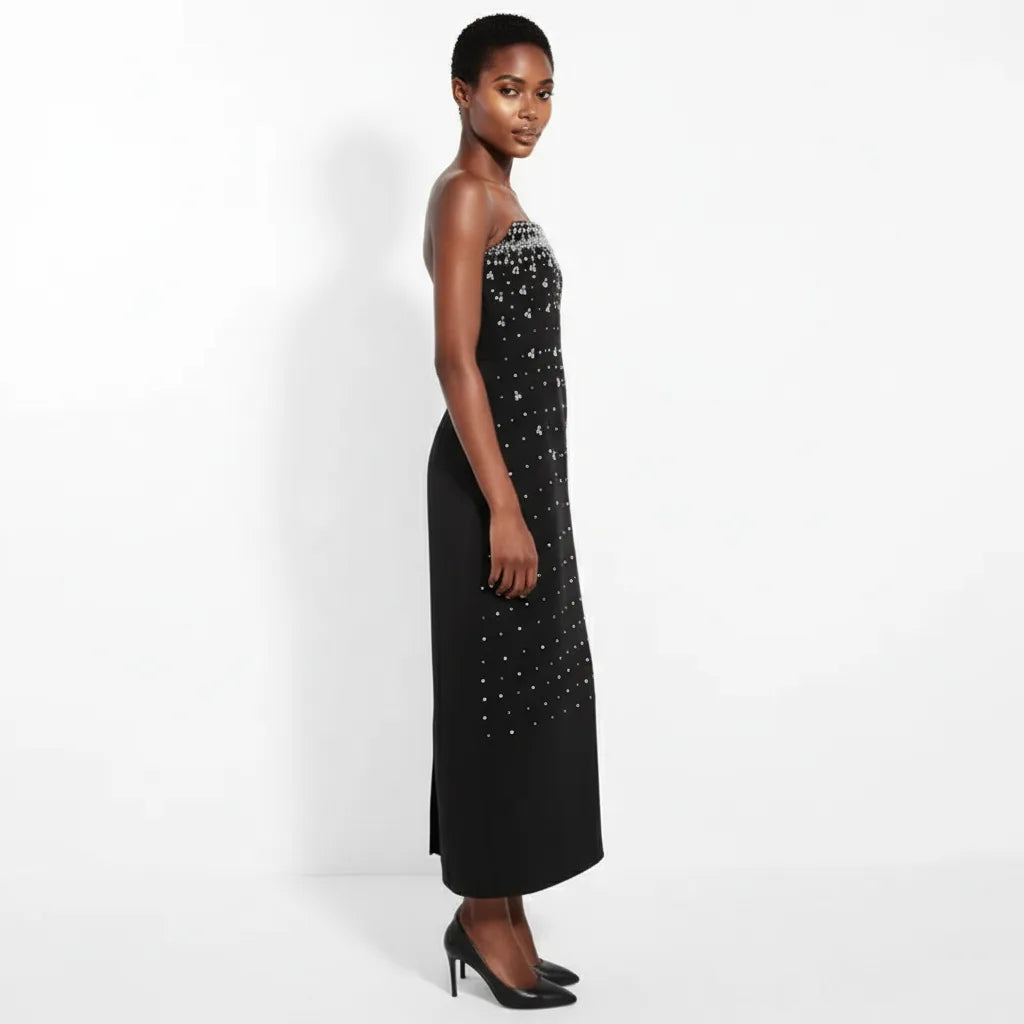 Woman wearing a black evening gown with silver embellishments on a white background