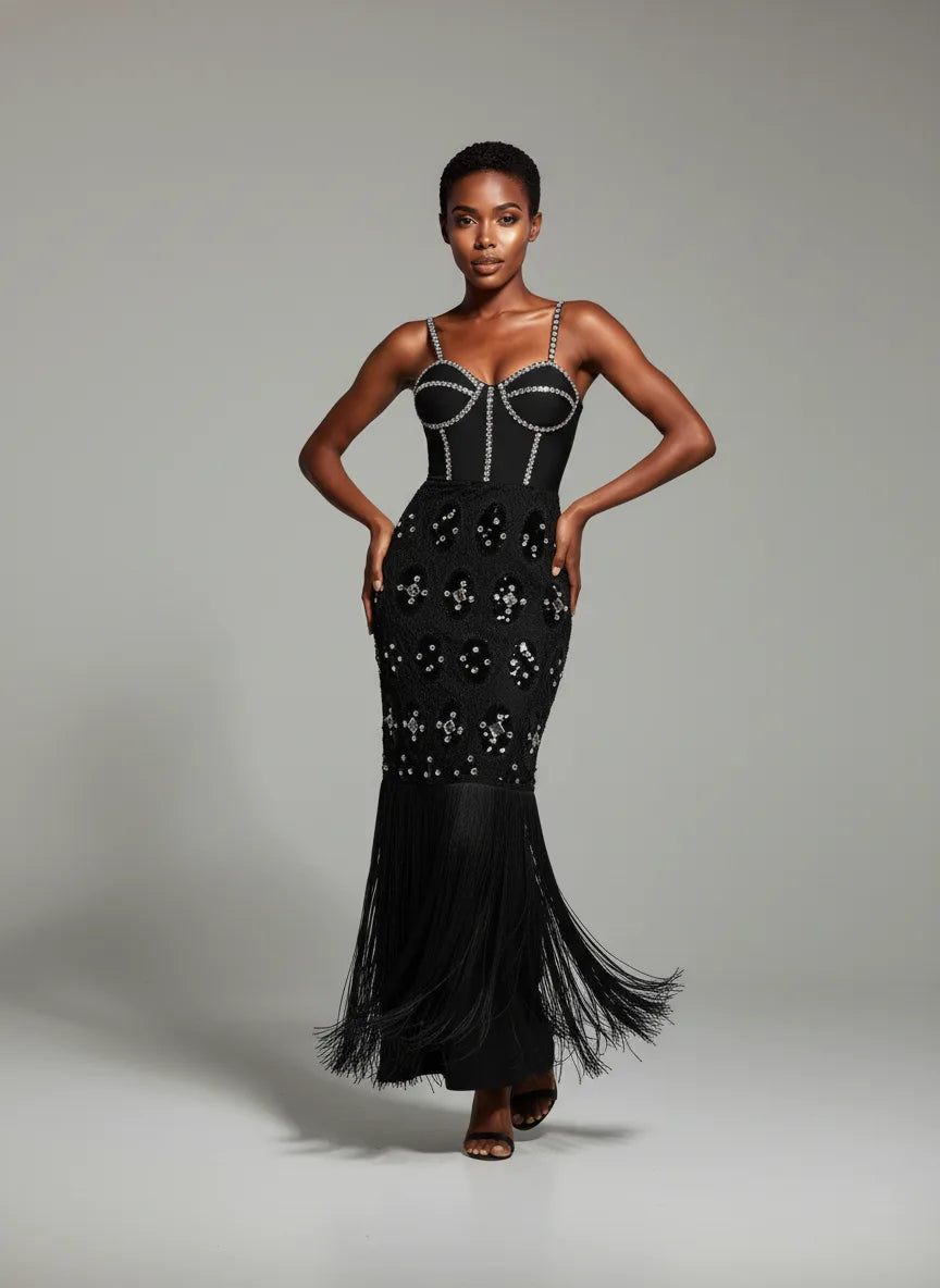 Woman wearing a black evening gown with intricate detailing on a gray background