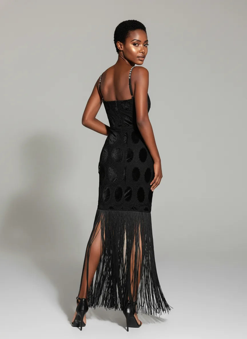 Woman wearing a black dress with fringe details on a plain background