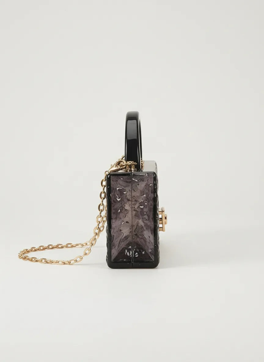 Black rectangular clutch with gold chain on a white background