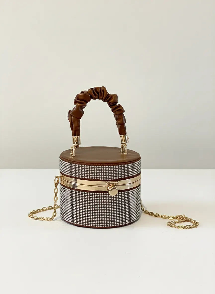 Designer handbag with brown handle and gold chain on a white background