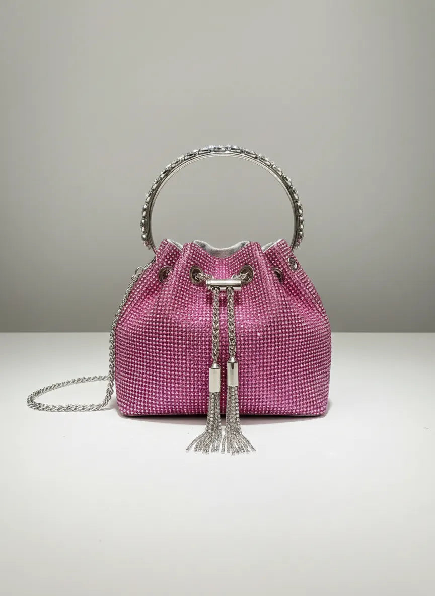 Pink handbag with silver chain and tassel on a light gray background