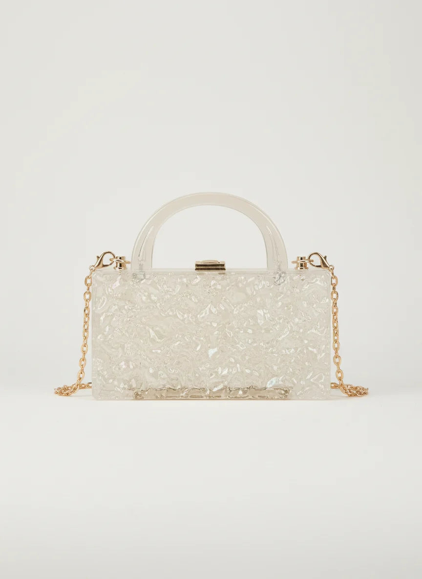 White glittery handbag with a gold chain on a light gray background