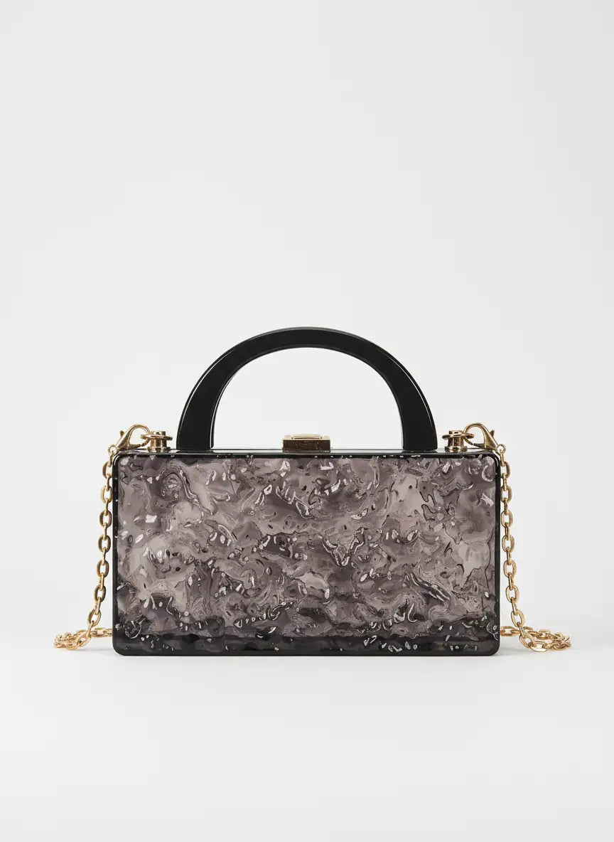 Black textured handbag with gold chain on a white background